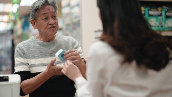 亚洲华人老年男子在药店向女药剂师寻求医疗用品方面的建议