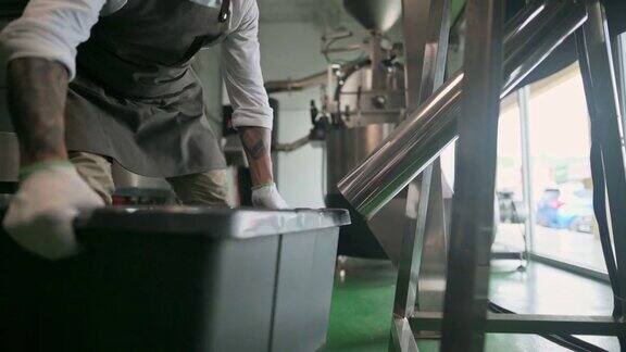 亚洲华人高级技工收集和检查烘烤咖啡豆后从冷却过程和去石在他的工厂落入桶
