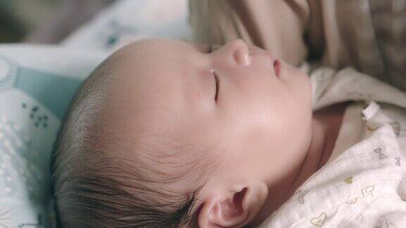 熟睡的亚洲新生婴儿的脸部特写在妈妈的怀抱里有一个开朗、可爱的心情