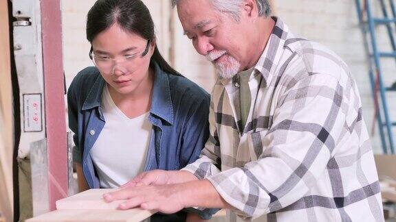 亚洲老人木匠教少女与木板在车间教育领导力家庭人小企业领导力愿景退休创新机会女性在STEM蓝领工人