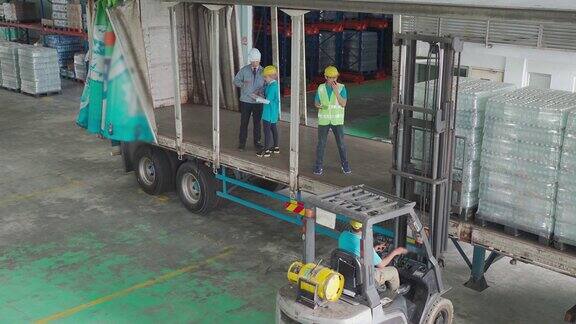 亚洲仓库工人用叉车将纸箱装到托盘上领班清点存货