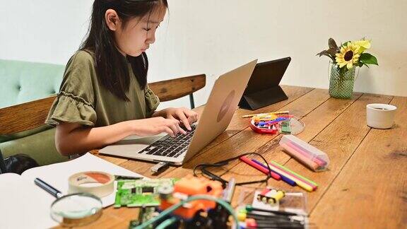 少女在家学习编程她正在用电脑手工制作机器人