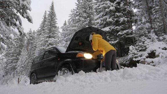 女人在雪地中抛锚的汽车旁打电话