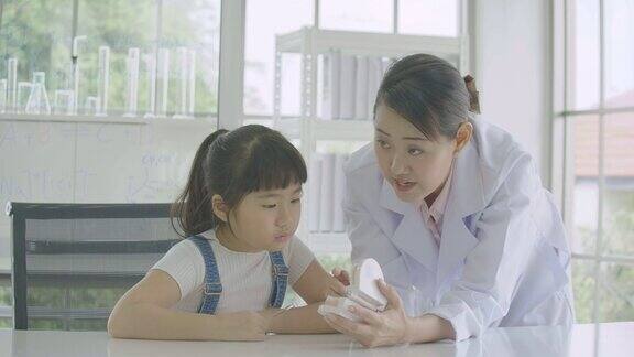 小亚洲学生女孩学习人体骨骼与颌骨模型在解剖课上科学和教育