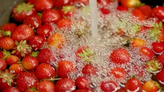 厨房水槽里水流在鲜红多汁的草莓上