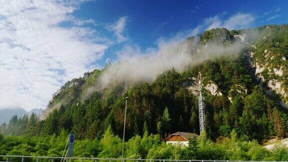 奥地利美丽的风景从行驶的火车或汽车的窗口看到的景色山顶上覆盖着森林和云彩的高山