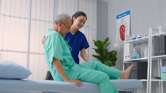 亚洲年轻女性治疗师在医院支持老年男性病人迷人的女性专科医生做物理治疗程序的老年成熟男性保健预约期间