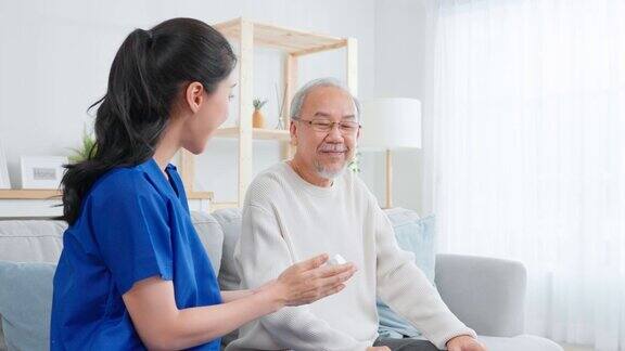 亚洲老年男性病人在护理之家与内科护士商量看家治疗师药剂师女孩拿着药瓶在客厅里给老男人解释处方