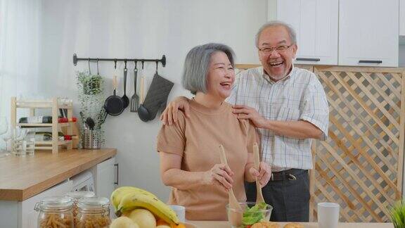 亚洲老年夫妇在家里的厨房里一起做沙拉幸福的家庭有魅力的年长成熟的夫妻享受退休生活在家里制作健康的食品健康幸福