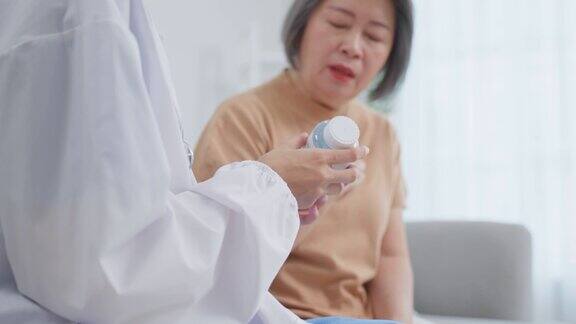 亚洲老年妇女病人咨询医生护士在疗养院护工治疗师药剂师女孩拿着药瓶向家中残疾的老年女性解释处方