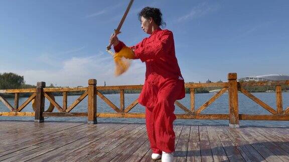 一位女士在湖边练太极剑