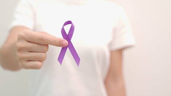 手握紫丝带为胰腺癌食管癌睾丸癌世界阿尔茨海默病癫痫狼疮结节病纤维肌痛和家庭暴力宣传月世界癌症日概念
