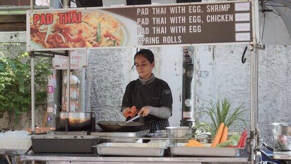 在泰国老城的一个街市上一个自信的女人在炒锅里做泰式炒粉