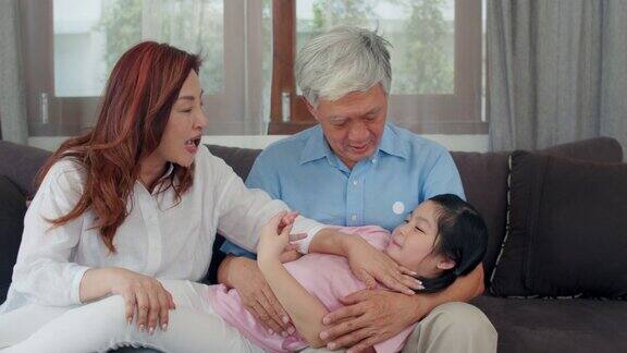 亚洲祖父母在家里和孙女聊天中国老年人、老一代、爷爷奶奶家人时间和小女孩孩子在客厅沙发上放松缓慢的运动