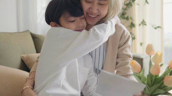 亚洲男孩拿着一束花拥抱他的母亲