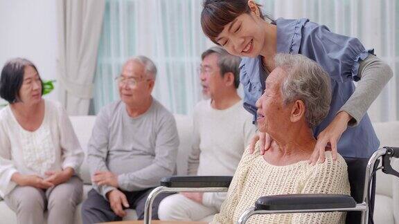 在养老院坐在轮椅上的亚洲老年妇女和亚洲年轻女性在家照顾而她的按摩亚洲祖母的肩膀和护士在养老院协助老年人