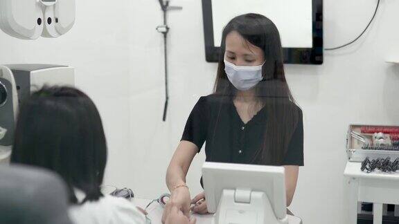 亚洲华裔女性眼科医生在检查光学实验室使用试验框架与儿童患者