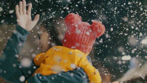 母亲和女儿玩在冬天的节日下雪