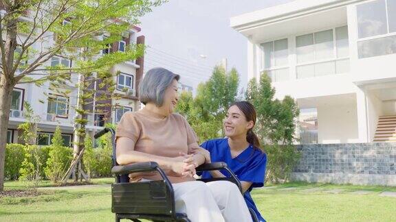 护理人员在户外照顾坐轮椅的残疾老妇人