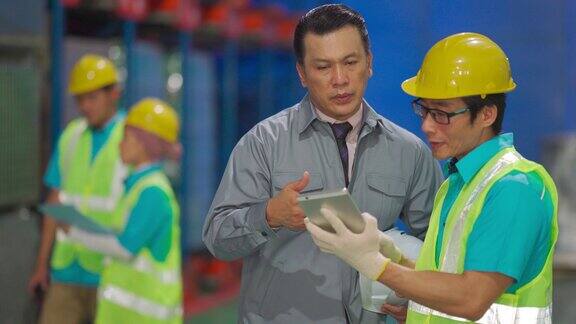 亚洲工厂经理与仓库领班讨论使用平板电脑进行仓库交货计划
