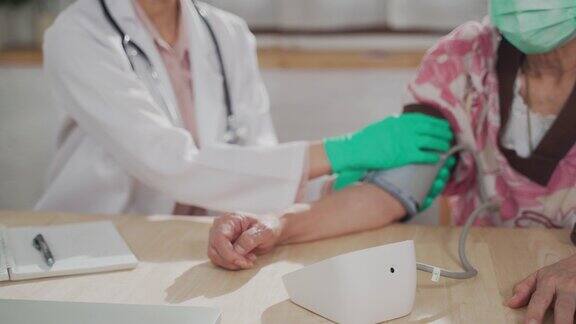 亚洲妇女医生在家里为老年妇女检查血压