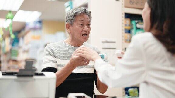 亚洲华人老年男子在药店向女药剂师寻求医疗用品方面的建议