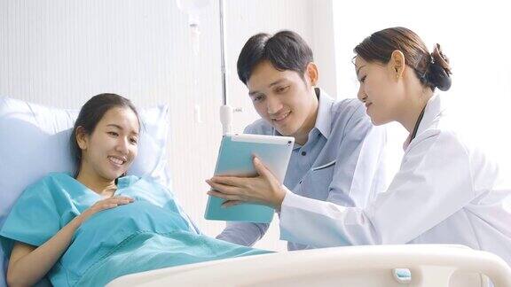 可爱的亚洲夫妇兴奋的父母看超声图像的数字平板电脑在病房