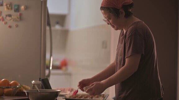 亚洲华人中年妇女戴着头巾在厨房的花生饼干上刷蛋黄