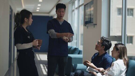在走廊喝茶的亚洲华裔医生和护士