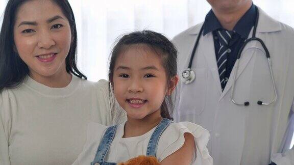 肖像亚洲母亲与6岁的小女孩访问儿科医生自信的微笑看着相机摆姿势在医疗诊所