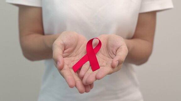 手握红丝带纪念12月的世界艾滋病日、获得性免疫缺陷综合征、多发性骨髓瘤癌症宣传月和全国红丝带周保健和世界癌症日