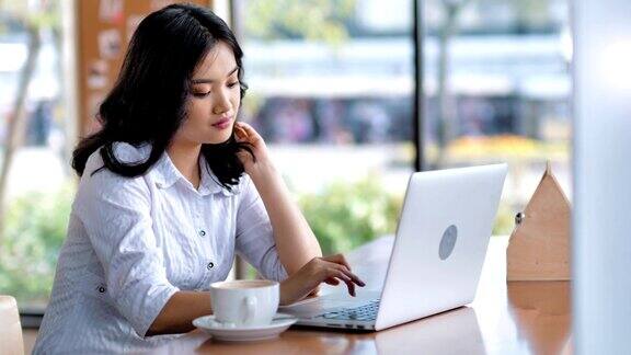 肖像迷人的自由职业者亚洲女人使用笔记本电脑写作文本