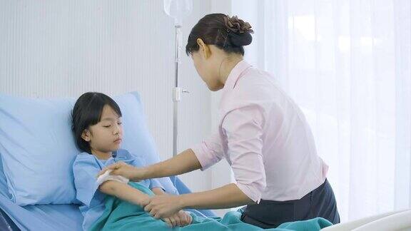 妈妈看着体温表给住院的小女儿量体温
