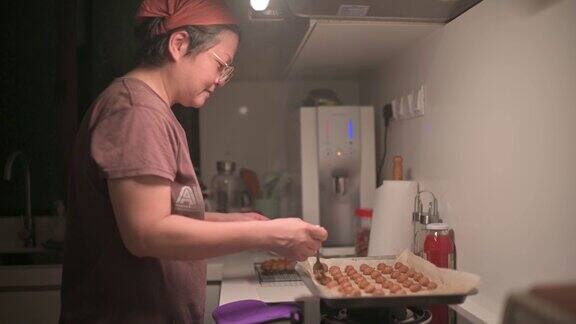 亚洲华人中年妇女在厨房拿起烤花生饼干