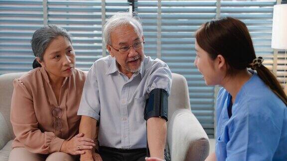 年轻的亚洲成年女性护士检查一位老年病人的血压女医生在安老院访问时用手提电脑检查并咨询健康结果同时跟进检查表
