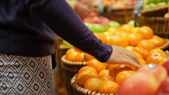 女人在超市购物挑选和购买橙子