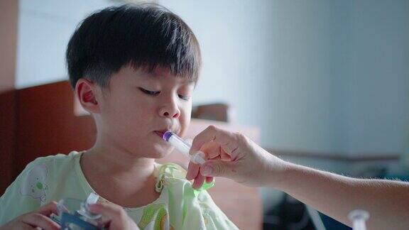 亚洲小男孩在医院用注射器服用液体药物
