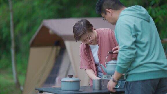 接近亚洲华人中成年夫妇在早上煮水准备咖啡在露营