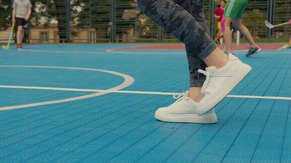 一个女孩的腿的特写一个女孩在篮球场上走着背景是人们在打地板球4k