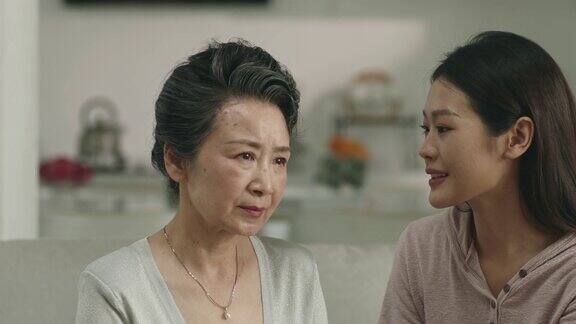 悲伤的亚洲老年母亲从成年女儿那里得到安慰