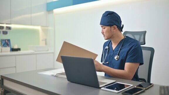 亚裔华人医生在医生办公室用笔记本电脑打字