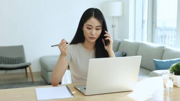 女人用手机聊天坐在办公桌前用笔记本电脑