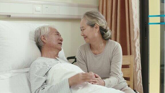 慈爱的亚洲老妇人在医院病房探望丈夫