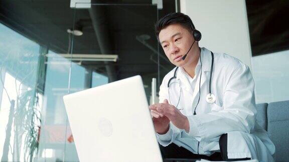 亚洲男性医生使用笔记本电脑和头戴式摄像头通过视频通话给病人提供建议与医生进行远程会诊男人聊天聊天聊天远程医疗