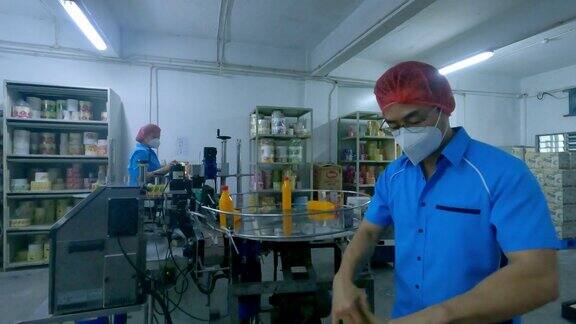 延时亚洲生产线工人在终点线将橙汁瓶装入纸盒