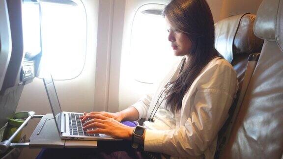 女商人在飞机上用笔记本电脑工作商务旅行