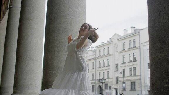 年轻的balerinа穿着白色的礼服在剧院的楼梯上以慢动作旋转芭蕾舞女演员在户外跳舞4k120fpsProresHQ