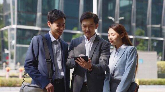 亚洲商人在城市街道上一起看手机