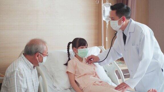 亚洲男医生戴着口罩来到康复室向躺在病床上的儿童病人询问健康问题男医生检查心率、脉搏和提供健康保健咨询