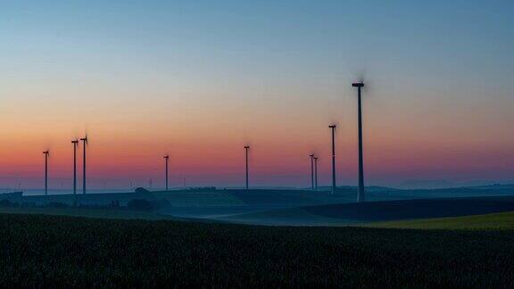 从黎明到日出的时间流逝拍摄的风力涡轮机在农村旋转